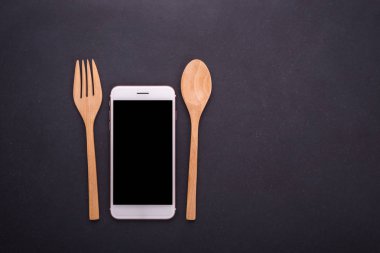Arka plan, konsantrasyon smartphone, kaşık ve çatalı siyah taş masa