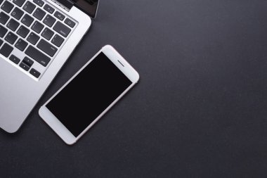 Modern smartphone ve siyah taş üstünde laptop tahta masa. Top vie