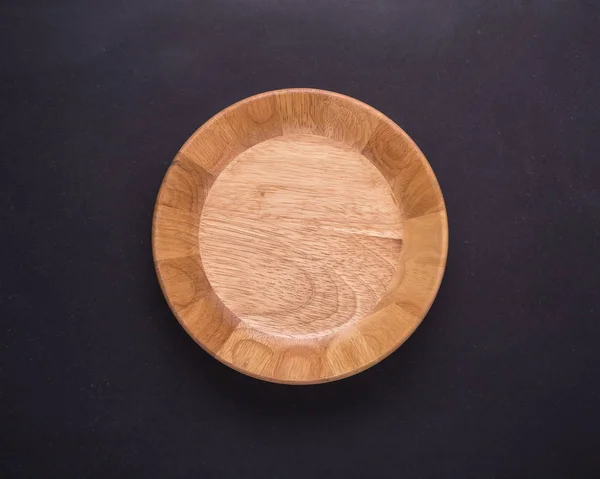 Bright empty wooden dish/bowl on black stone board background — Stock Photo, Image