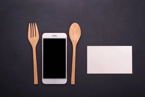 Smartphone, lepel en vork op zwarte steen tabel achtergrond, conc — Stockfoto