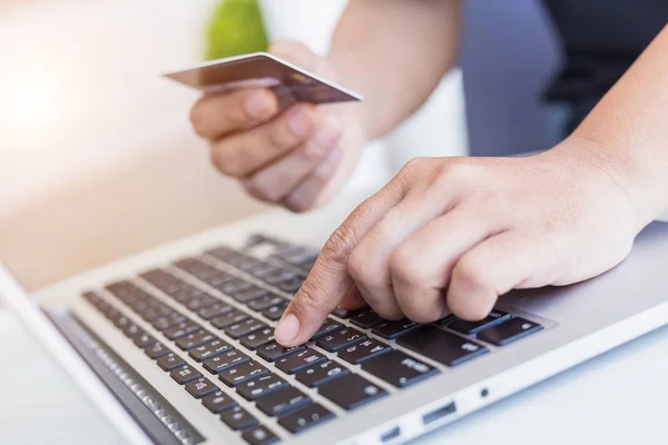 Mulher mãos segurando cartão de crédito na frente do laptop na mesa . — Fotografia de Stock