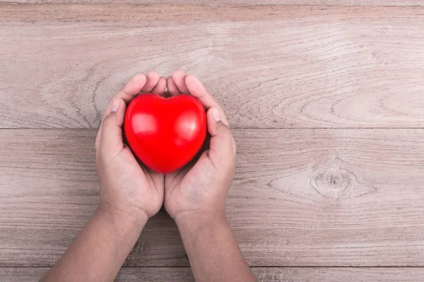 Kärlek koncept: Kvinna händer med rött hjärta brun trä fliken — Stockfoto
