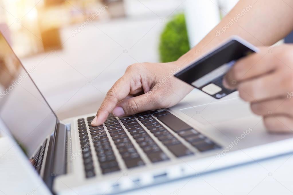 Woman hands holding credit card in front of laptop on the desk. 