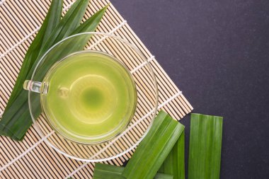 Pandan Juice in clear glass and fresh Pandan Leaves on black sto clipart