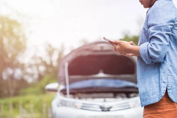 Žena používající smartphone před její rozbité auto na silnici. C — Stock fotografie