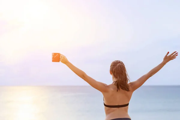 Frau trinkt Kaffee in roter Tasse und entspannt sich am tropischen Strand — Stockfoto