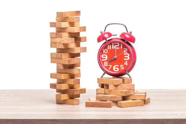 Pile of blocks wood game and red alarm clock on wooden table. St