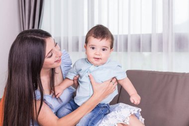 Anne oğlu ile oynuyor. Sağlıklı bebek gülümseyerek. Beyaz