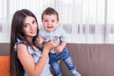 Anne oğlu ile oynuyor. Sağlıklı bebek gülümseyerek. Beyaz