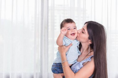 Anne oğlu ile oynuyor. Sağlıklı bebek gülümseyerek. Beyaz