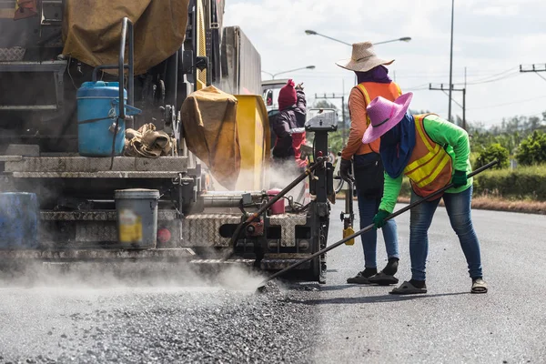 Trabajador que opera el proceso de construcción de una nueva carretera de asfalto en el —  Fotos de Stock