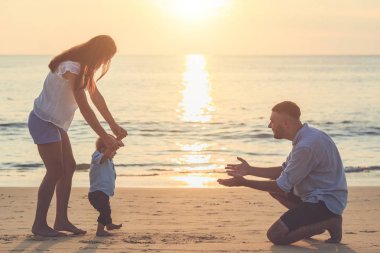 Aile sahilde, anne oğlunun elini tutarak ve yürüyüş,