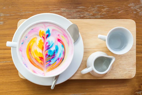 Bunter Regenbogen-Latte-Kaffee in weißer Tasse auf Holztisch mit — Stockfoto