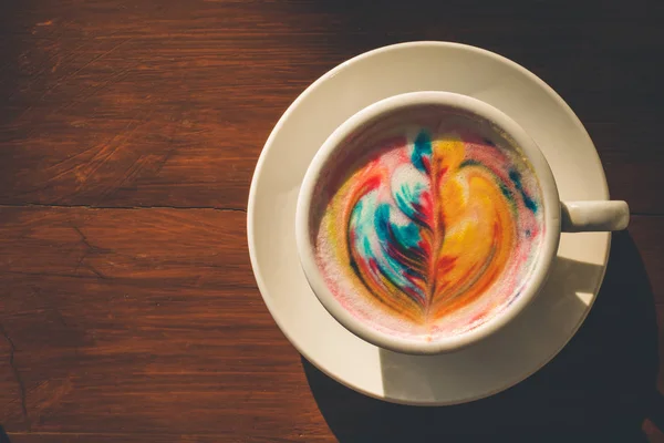 Bunter Regenbogen-Latte-Kaffee in weißer Tasse auf Holztisch mit — Stockfoto