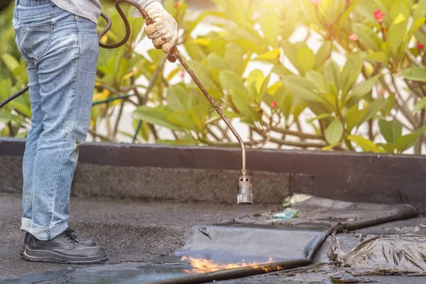 Grupp av arbetstagare installera tjära folie på taket av byggnaden. — Stockfoto