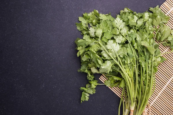 Vista superior verde fresco hoja de cilantro tailandés sobre piedra negra — Foto de Stock