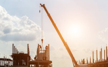 Çatıda çalışan inşaat işçilerinin silueti.