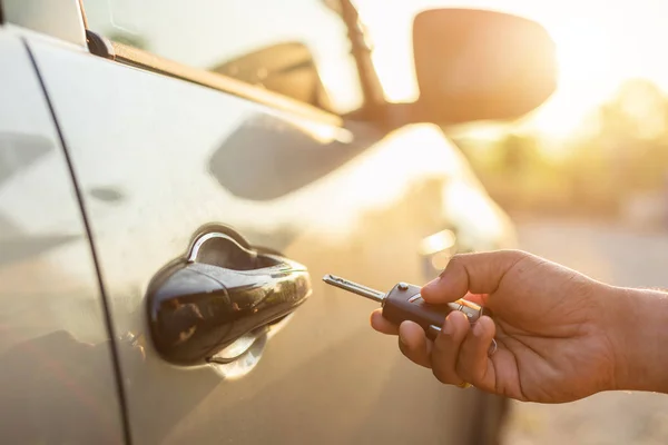 Hand hält ferngesteuerte Autoschlüssel und drückt die Taste öffnen oder verriegeln — Stockfoto