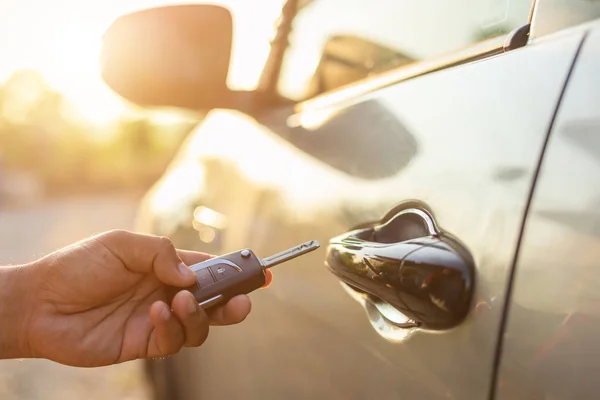 Ruka drží dálkové klíče od auta a stiskněte tlačítko otevřít nebo zamknout — Stock fotografie