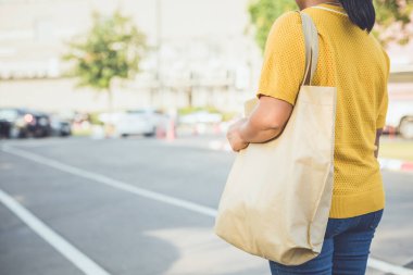 Woman using cotton bag in shopping center to replace plastic bag