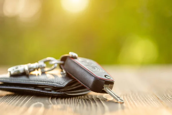 Neue Autoschlüssel mit schwarzem Lederetui auf Holztisch. Autotasche — Stockfoto