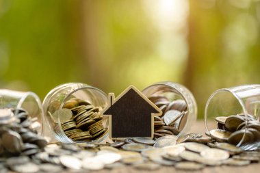 Ahşap ev modeli ve ahşap masadaki bozuk para yığını. Para tasarrufu