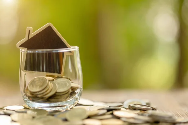 Houten huismodel en muntenstapel op houten tafel. Besparingen — Stockfoto