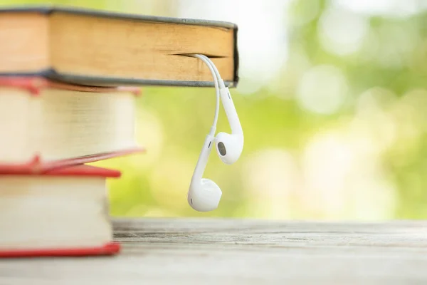 Book and white earphone on wooden table with abstract green natu — Stock Photo, Image