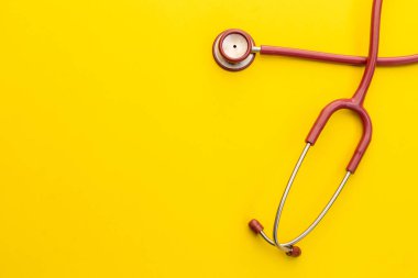 Sarı arka planda kırmızı steteskop. Kalp ya da sağlık kontrolü kavramı için