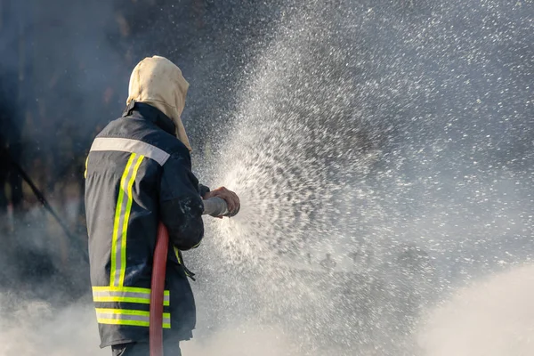 消防士や消防士は 火災を防ぐために大きな水のホースから水を噴霧 — ストック写真