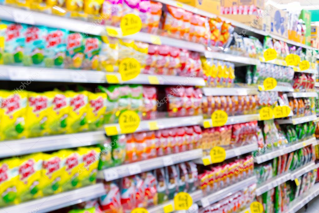 Blurred background of the fast food snacks for sale on supermarket shelf.