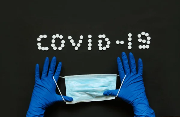 Doktorların ellerinde koruyucu eldivenlerle tıbbi maske. Mavi arka plan. Coronavirus konsepti. Dünyada salgın hastalık.