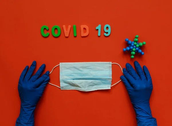 Doktorların ellerinde koruyucu eldivenlerle tıbbi maske. Mavi arka plan. Coronavirus konsepti. Dünyada salgın hastalık.