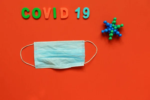 Siyah arka planda beyaz hapların tıbbi maskesiyle yazdığı Covid-19 yazısı.