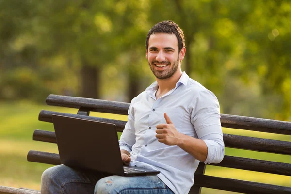 Empresario usando portátil y mostrando el pulgar hacia arriba — Foto de Stock