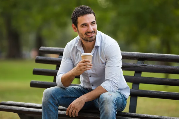 Бизнесмен пьет кофе в парке — стоковое фото