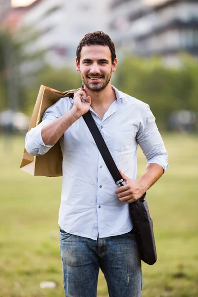 Empresário com sacos de compras em pé no parque — Fotografia de Stock