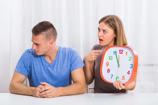 Angry wife showing clock to her husband — Stock Photo, Image