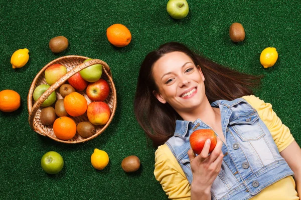 Женщина ест яблоко, когда лежит на траве — стоковое фото