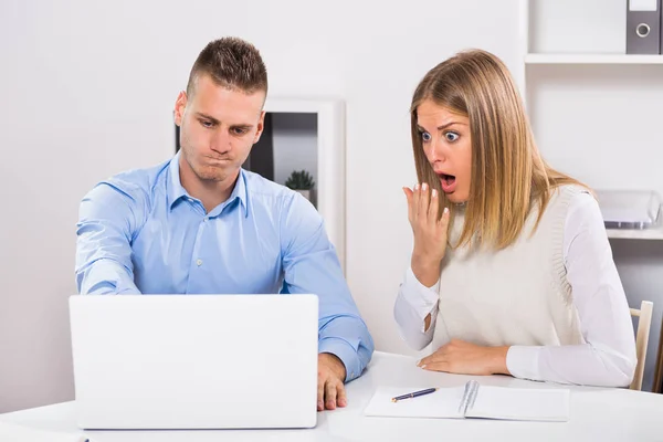 Беспокойный бизнесмен и деловая женщина в панике глядя на ноутбук — стоковое фото