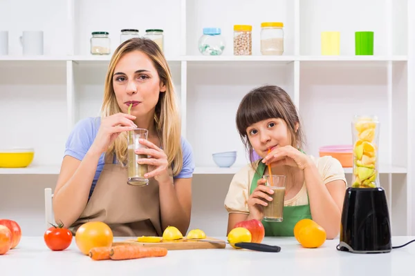 母亲和她的女儿制作和饮用果汁 — 图库照片