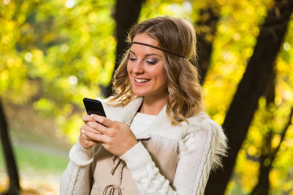 Boho meisje SMS bericht in het park. — Stockfoto