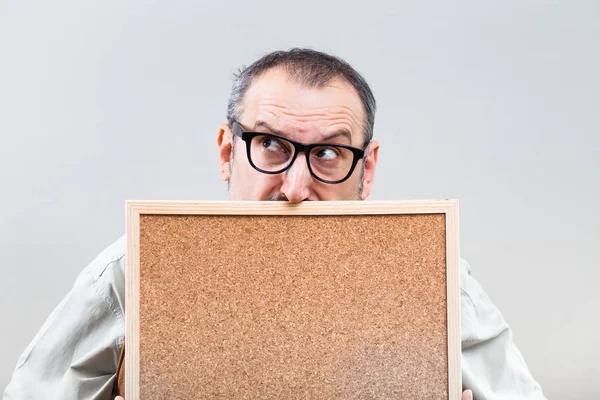 Нервный бизнесмен держит пустую пробковую доску — стоковое фото