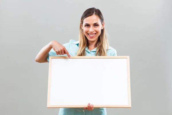 Bela enfermeira apontando para quadro branco — Fotografia de Stock