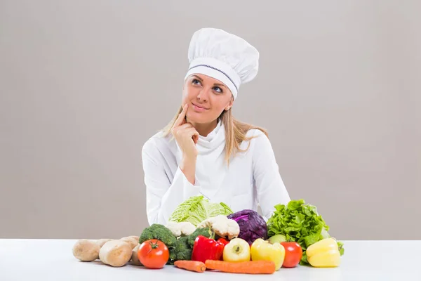 Female chef with bunch of vegetable thinking — Stock Photo, Image