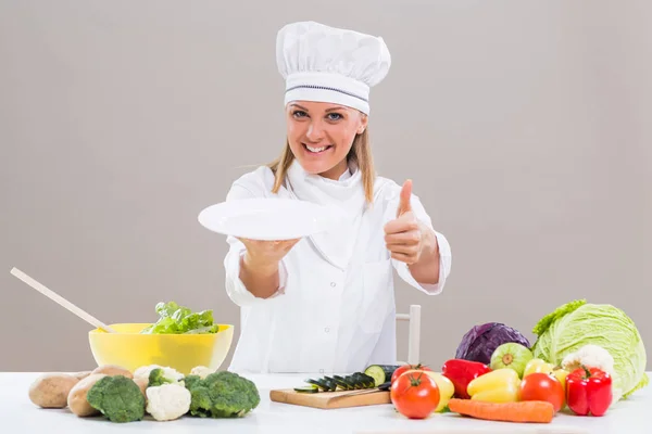 Kvinnlig kock visar plattan och tummen — Stockfoto