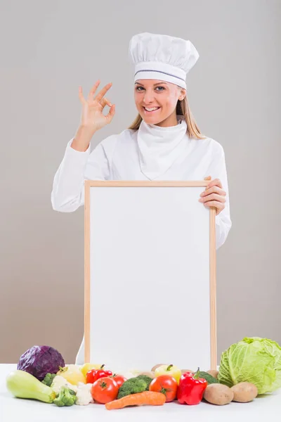 Chef donna con lavagna bianca e verdure che mostrano segno ok — Foto Stock