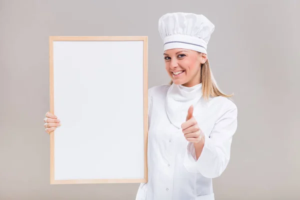 Kvinnlig kock visar whiteboard och tummen — Stockfoto