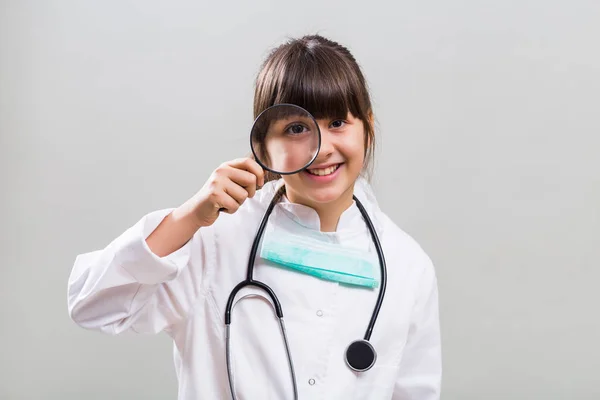 Little doctor looking through loupe. — Stock Photo, Image