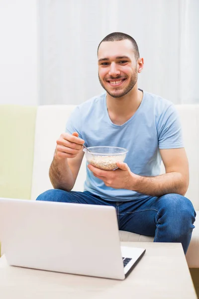 Homme prenant le petit déjeuner et utilisant un ordinateur portable — Photo